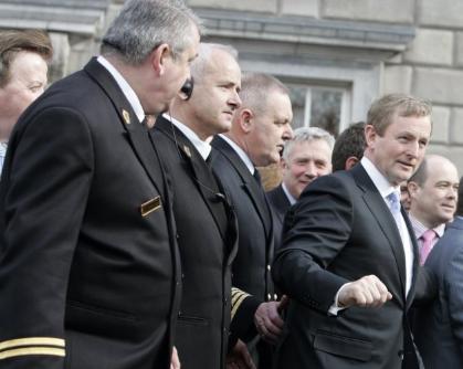 Ushers, wearing black suits with gold cuffs, escorting Enda Kenny from Leinster House